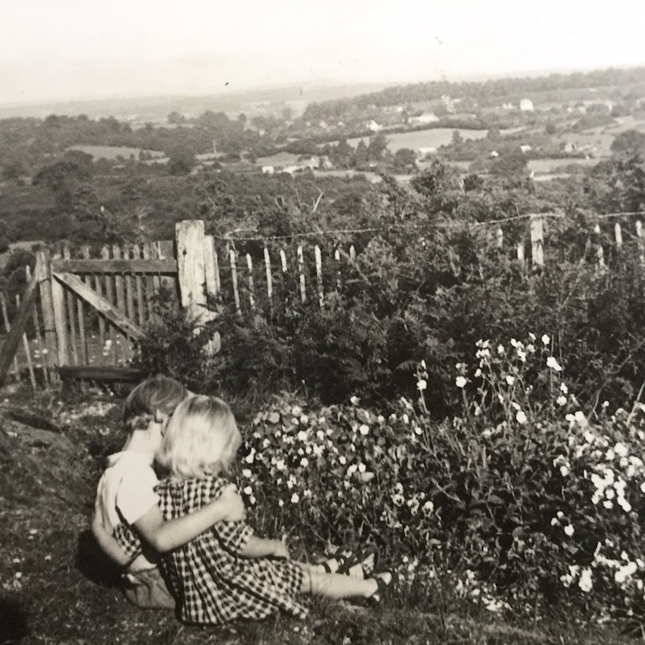 Two children, Christopher and Danae Charman, sitting in a garden overlooking fields and trees